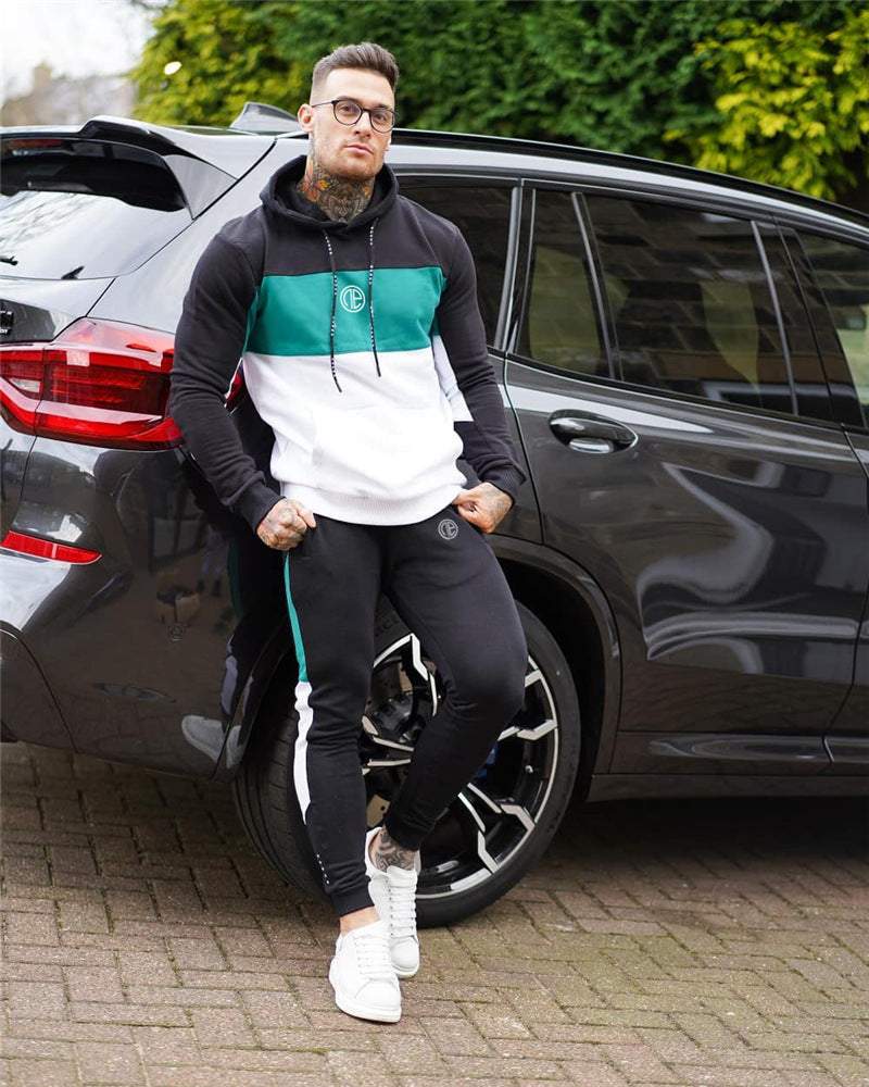 Man wearing fitness suit splicing contrast color hooded suit standing by black SUV outdoors