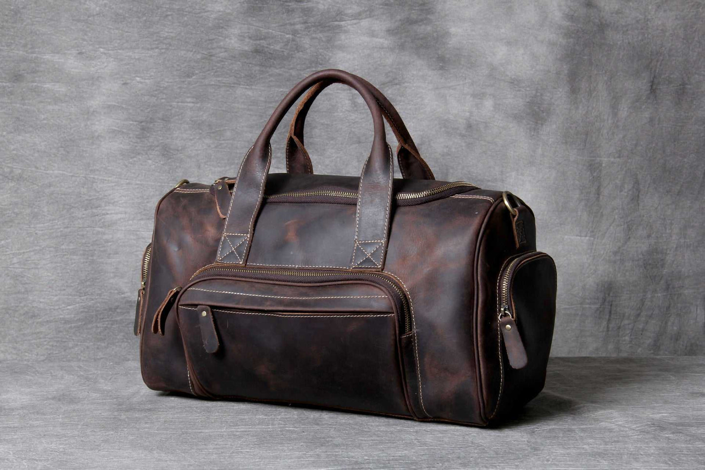 Dark brown genuine leather big travel bag with soft handles and multiple zipper pockets, unisex European and American retro style hand luggage bag.