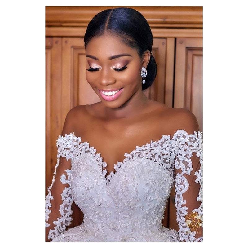 Bride wearing a white custom wedding gown with lace and pearl detail, featuring off-shoulder three-dimensional cut design