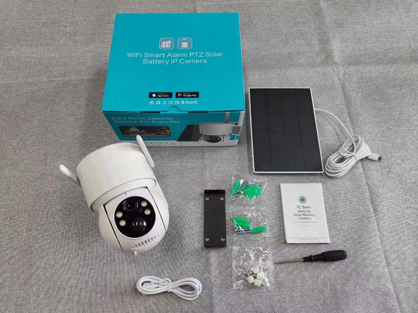 Motion detection audio video surveillance camera with WiFi, solar panel, mounting bracket, screws, screwdriver, power cord, and user manual on gray surface.