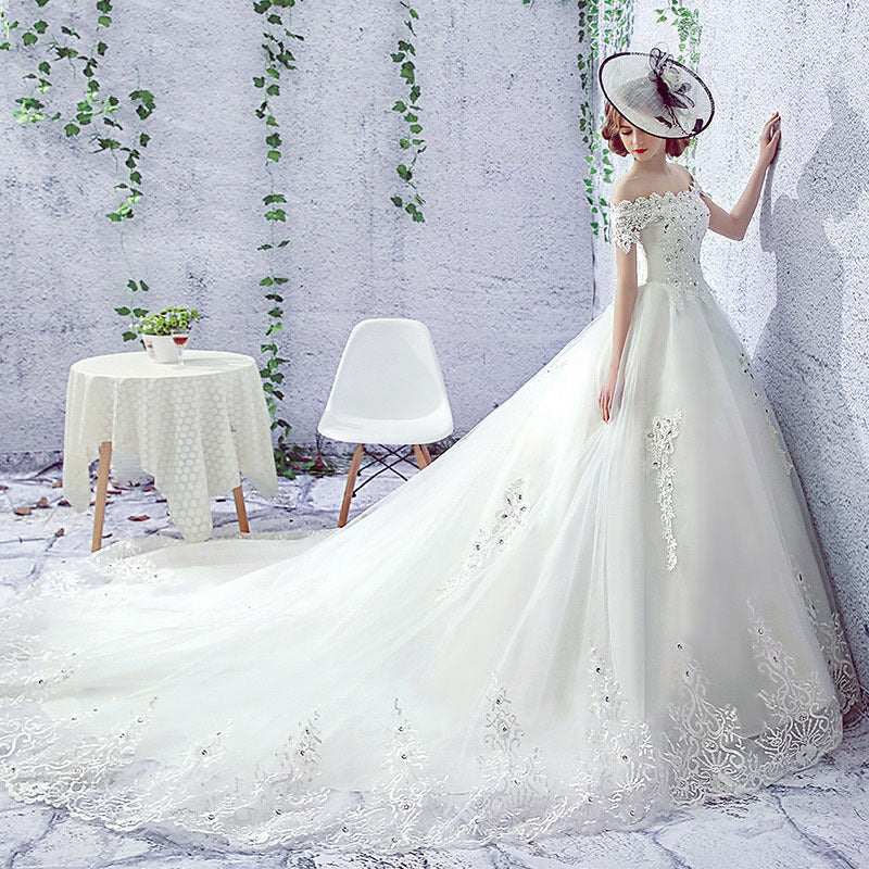Elegant one-shoulder wedding dress bride with long trailing French veil and intricate lace detailing