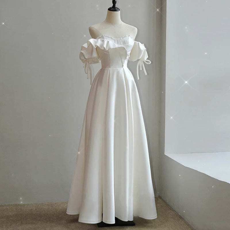 White satin light wedding dress with off-shoulder ruffled neckline and puff sleeves on mannequin