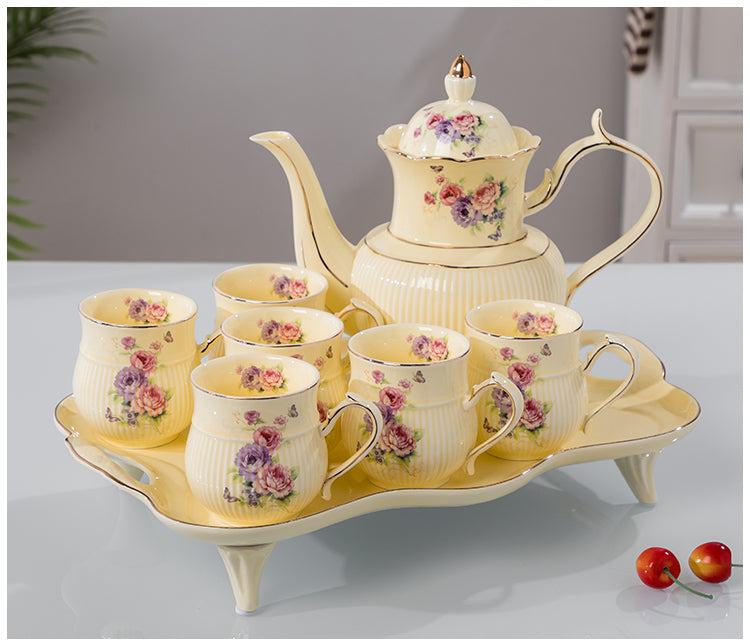 Elegant yellow ceramic water set with floral design, including teapot and six cups on matching tray