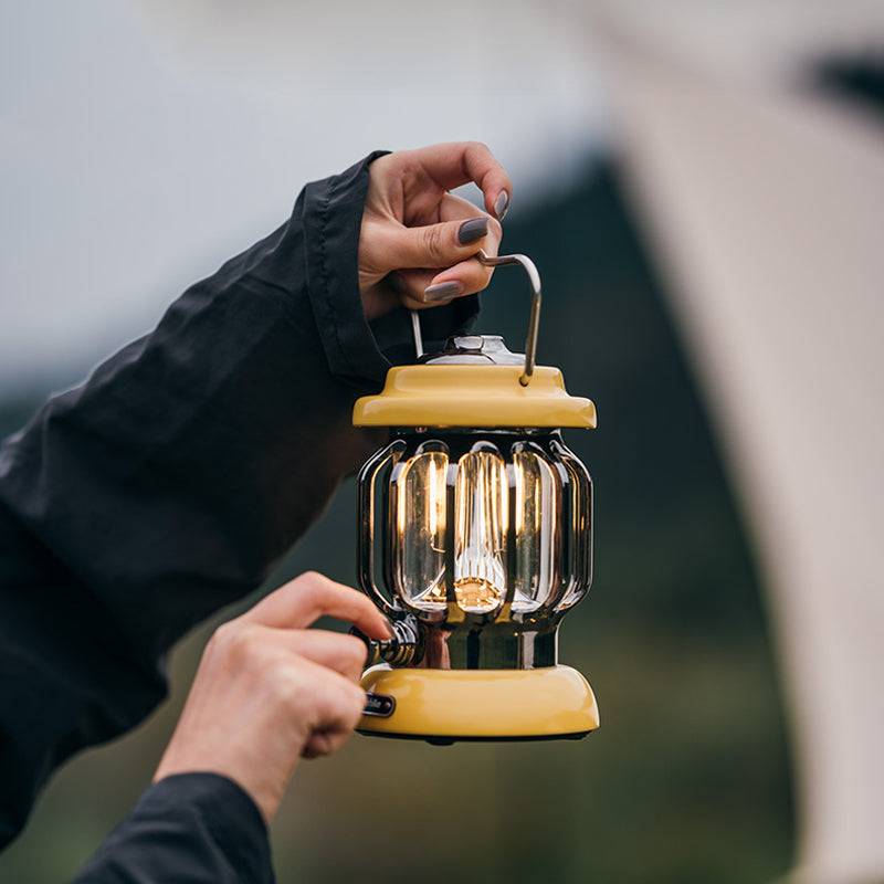 Hand holding yellow camping outdoor atmosphere light lantern with warm LED glow