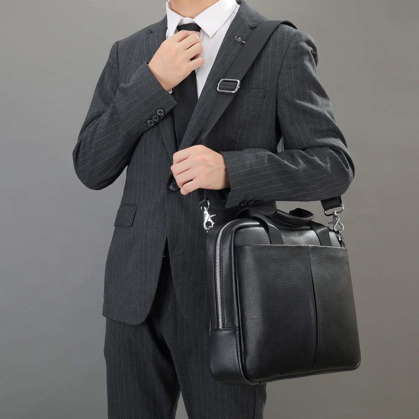 Black leather computer handbag with large capacity worn as one-shoulder bag by man in suit