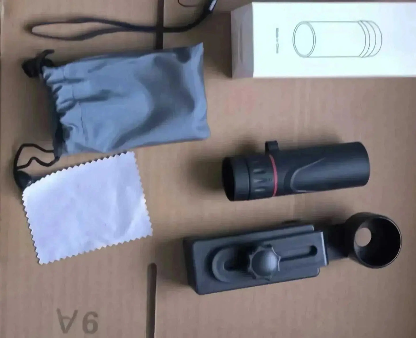 2000x25 HD monocular telescope with holder, soft pouch, cleaning cloth, and packaging box on a cardboard surface