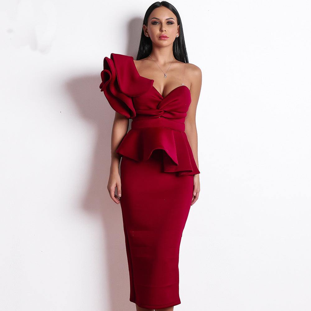 Woman wearing a red sexy strapless evening dress with large floral shoulder detail and peplum waist, standing against a white background.
