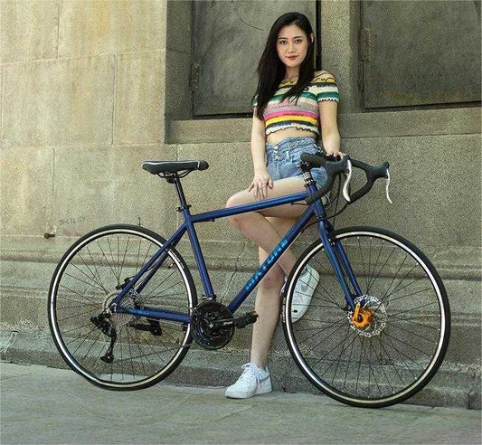 woman standing next to blue aluminum alloy road bike with flat handlebar against stone wall background