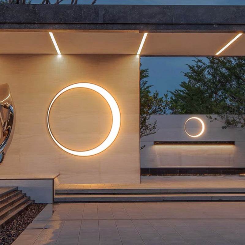 Outdoor simple round wall lamp in stainless steel with warm white LED lighting on exterior wall at dusk