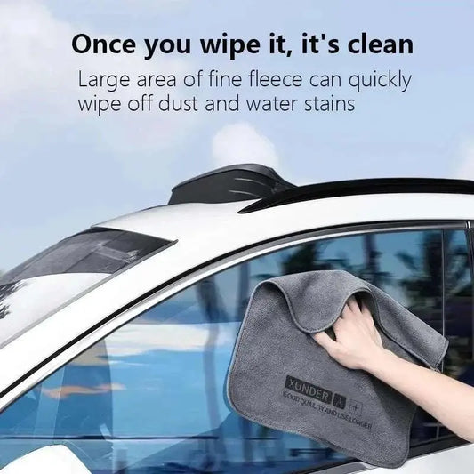 Grey microfiber car wash towel wiping car window for dust and water stain removal